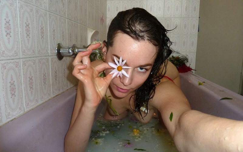 Совершеннолетняя девушка плескается ванне с цветами